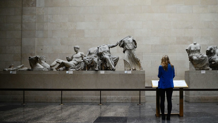 A woman looks at the Parthenon Marbles, a collection of stone objects.