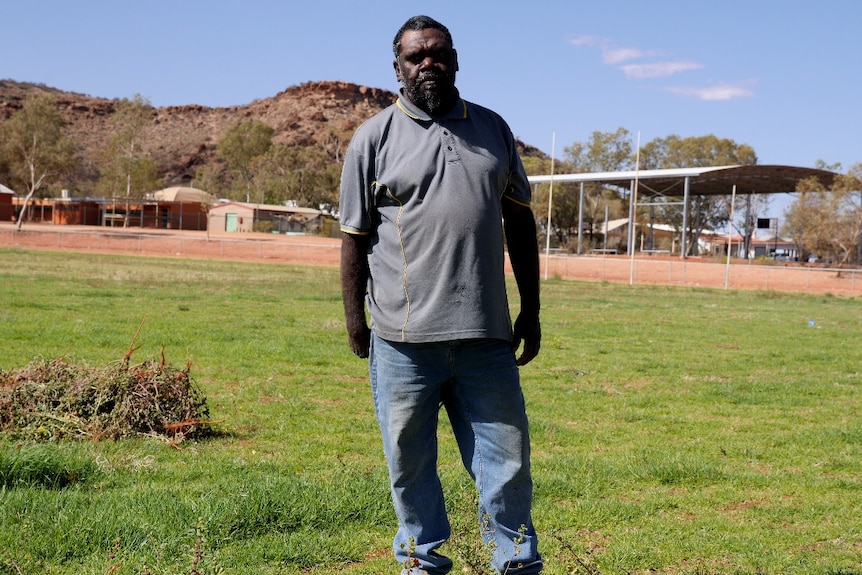 A man stands on a green grassed oval