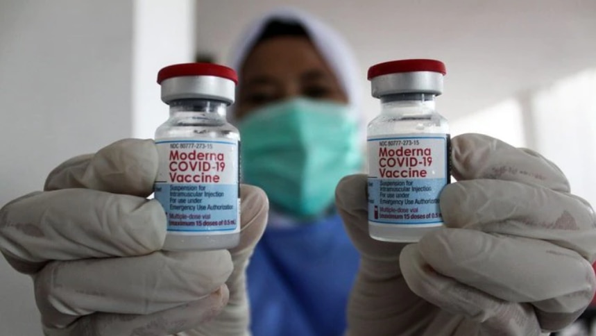A health care worker holds two Moderna vaccines.