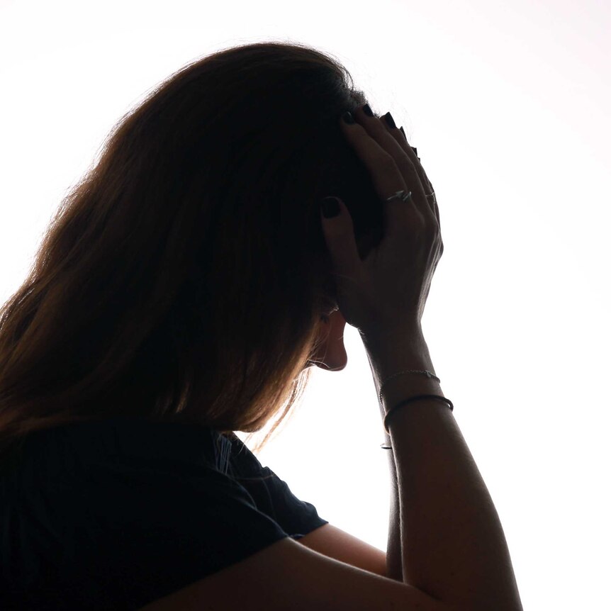 Stock image of a woman holding her head in her hands.