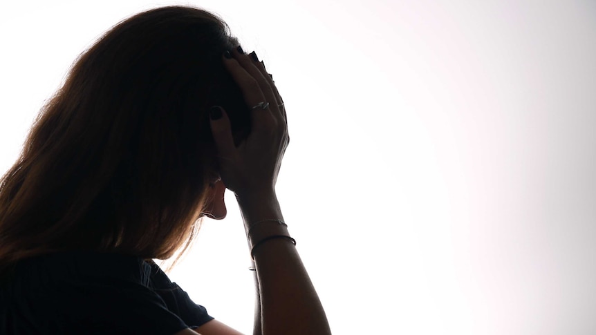 A woman holds her head in her hands