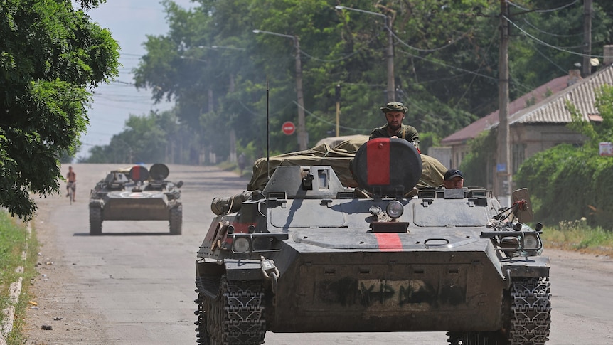 Man pokes head out of tank as it drives down a Ukrainian street