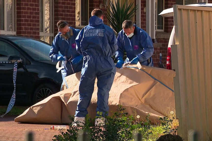 Three police officers outside a house gathering evidence.
