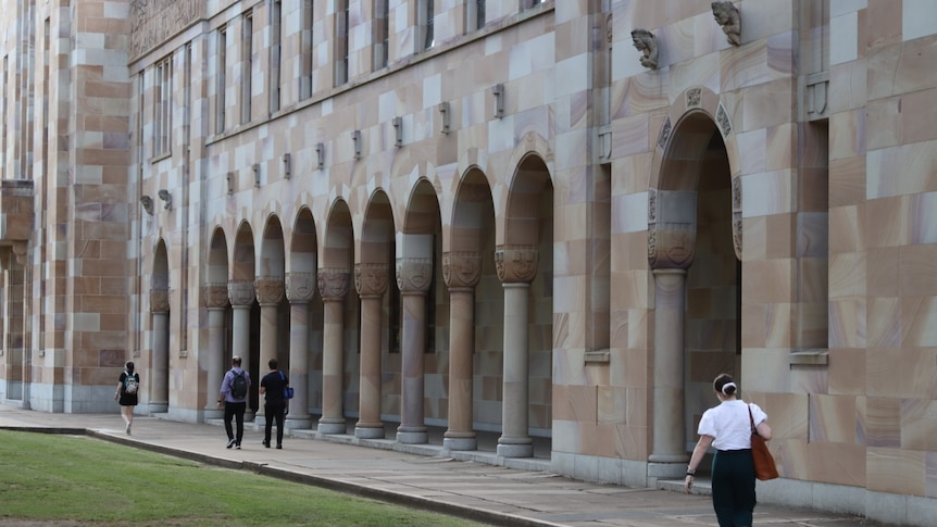 people walking past large sandstone arches in uq st lucia's great court
