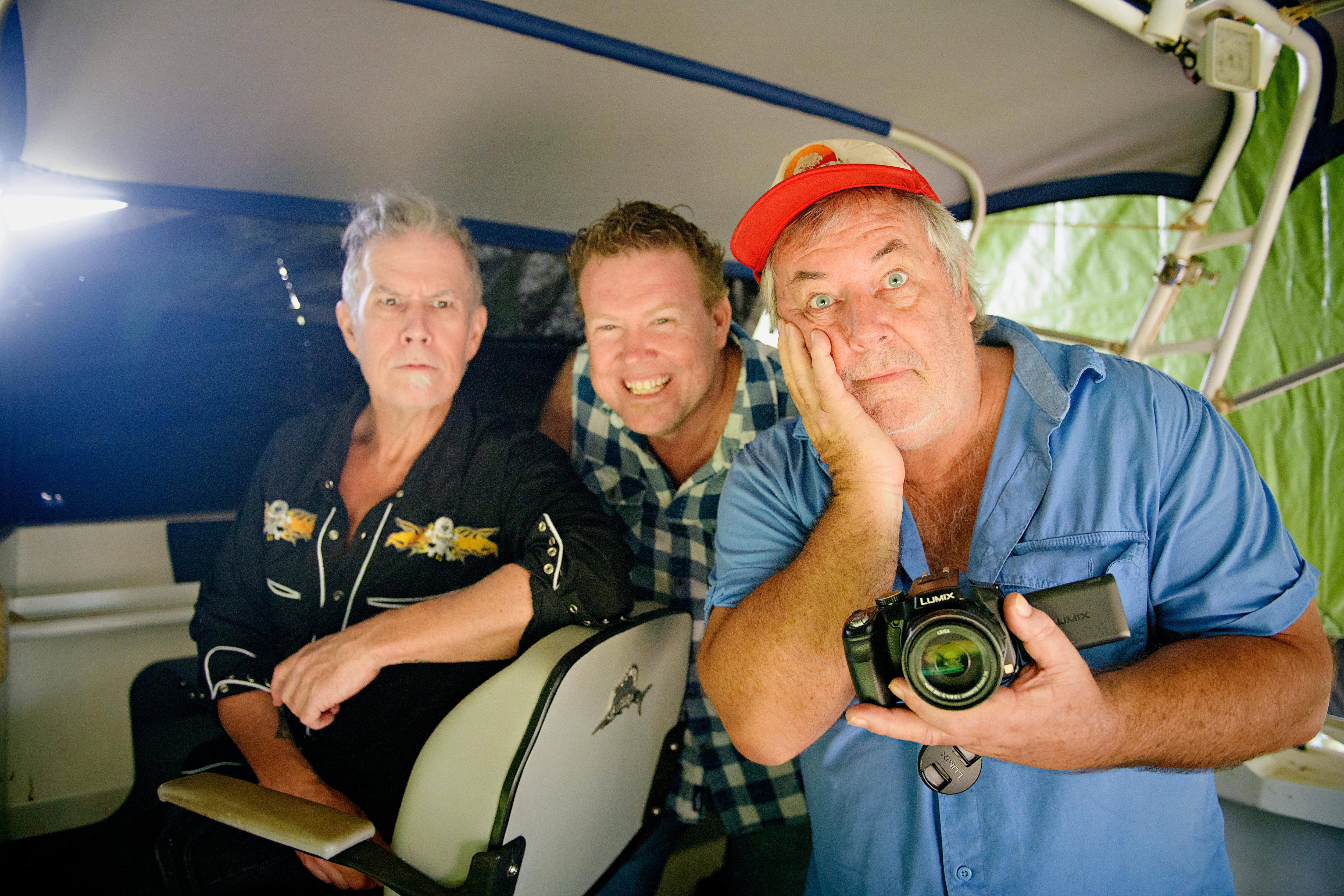 three men making silly faces inside a boat