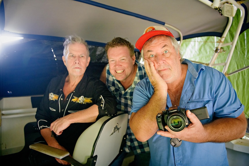 three men making silly faces inside a boat