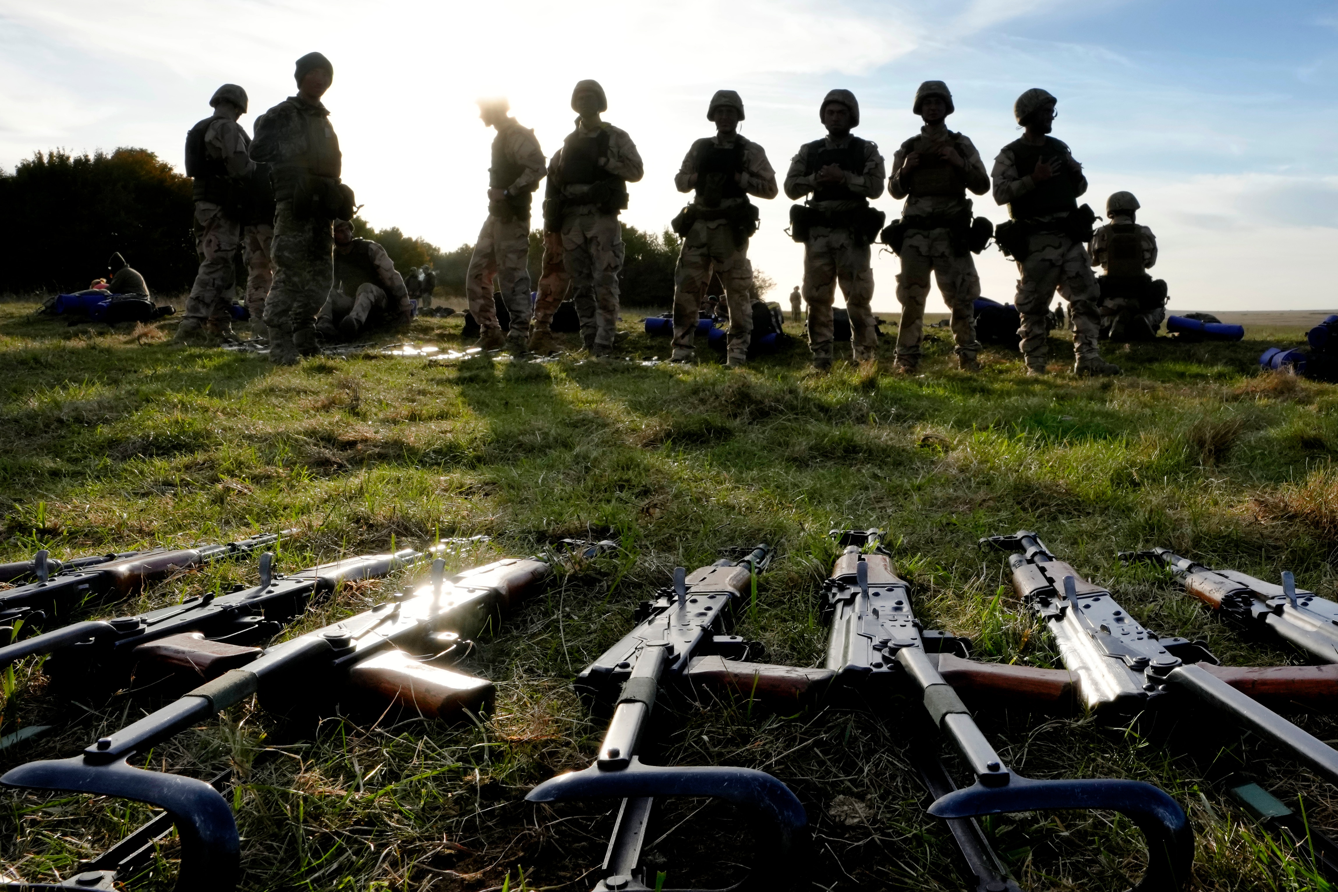 Weapons lie on the ground as Ukrainian personnel take a break during training at a military base with UK Armed Forces.