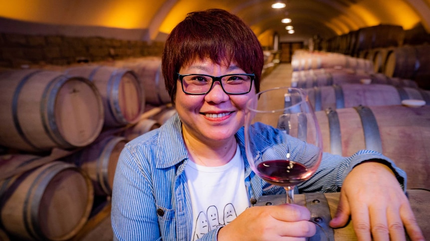 Wang 'Crazy' Fang in a wine cellar with some red wine in a wine glass, ready to sample