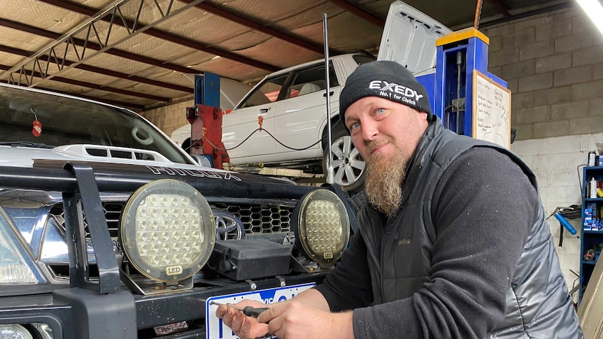 Wagga Wagga mechanic Scott Rohrich unscrewing a Victorian number plate