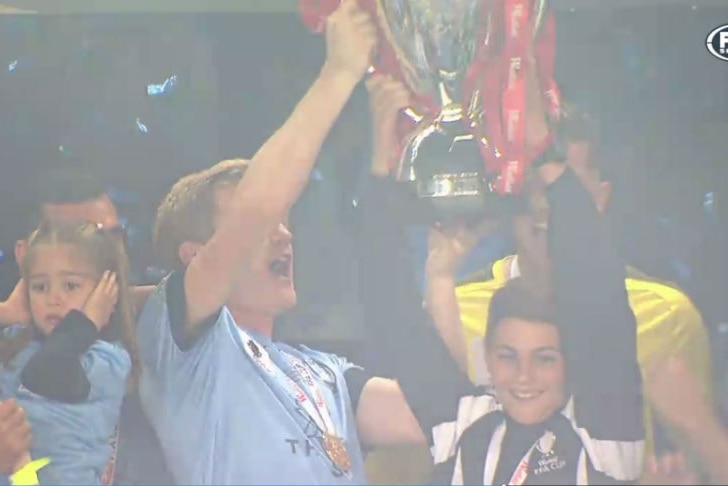 The ball boy raises the FFA Cup with Sydney FC players.