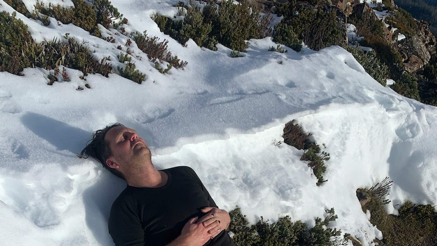 Keith Deverell, CEO of Music Tasmania, lies in the snow