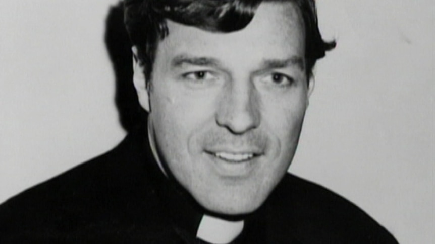 A black-and-white photograph of George Pell smiling in priest's attire.