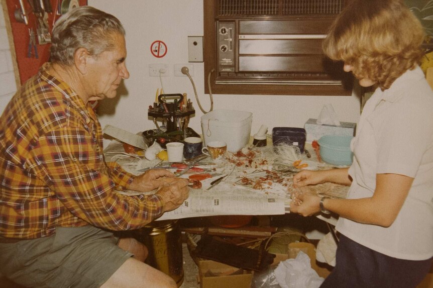 An older man and a young woman sitting at a table with bits of flesh on it.
