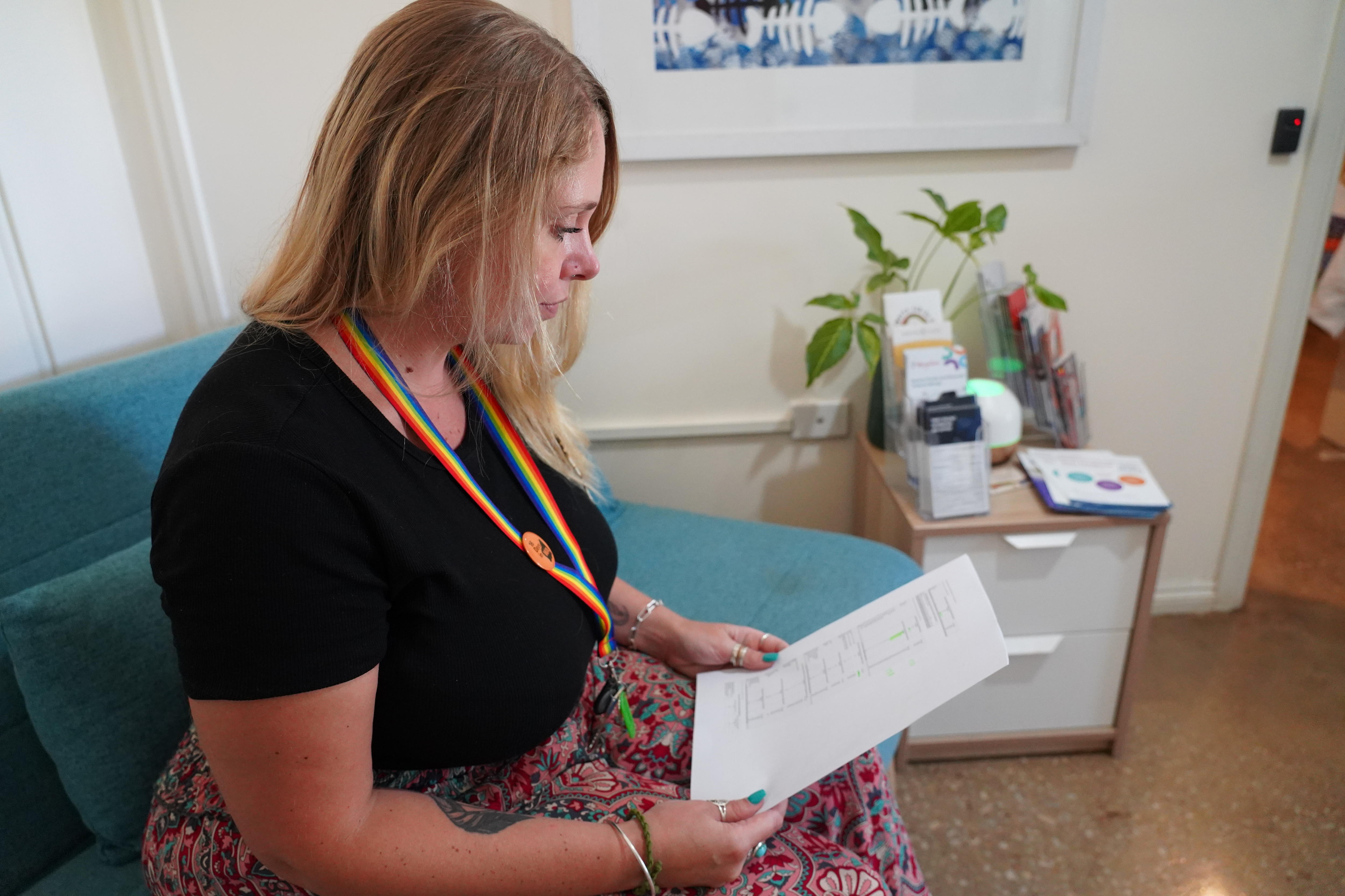 Uma mulher sentada em uma mesa lendo uma folha de papel. 