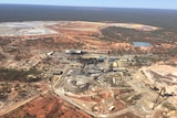An aerial shot of a mine in red dirt with bushland surrounding it
