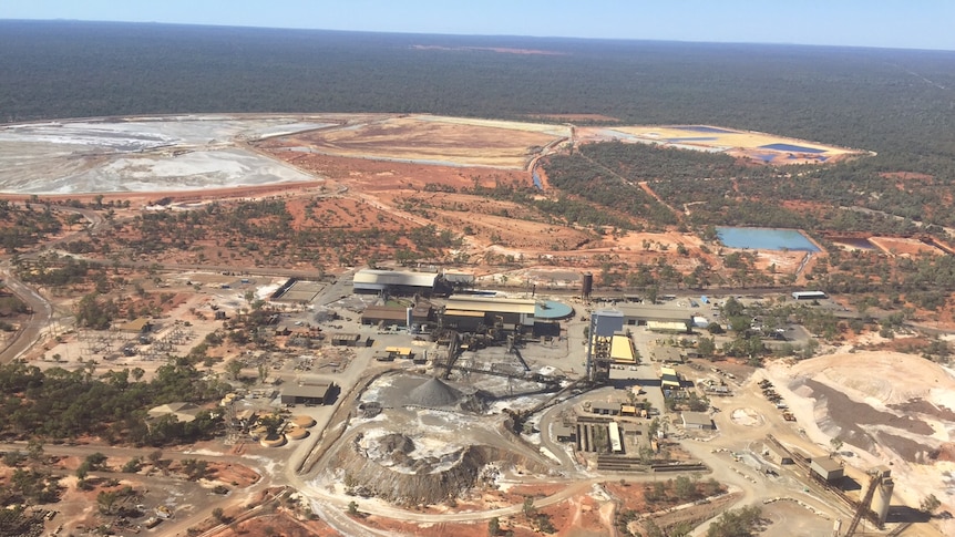 An aerial shot of a mine in red dirt with bushland surrounding it