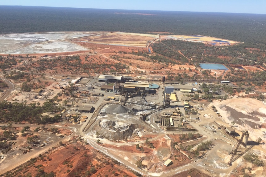 An aerial shot of a mine in red dirt with bushland surrounding it