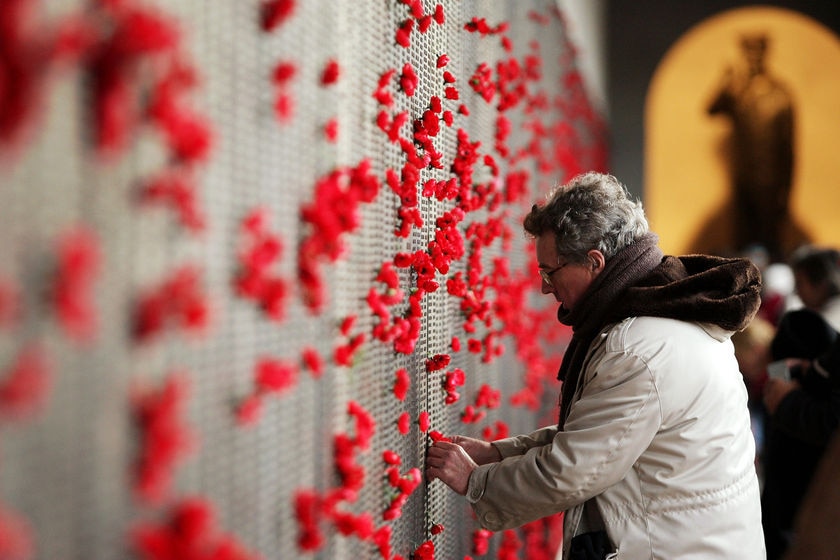 A man places a poppy on the Roll of Honour for World War I at the Australian War Memorial