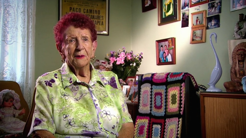 An elderly woman sits in her living room