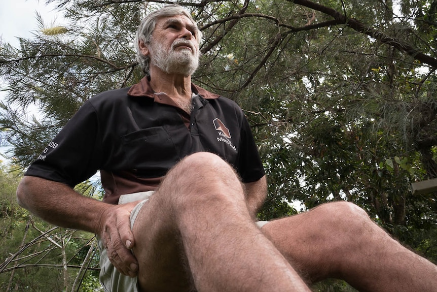 A man sitting down with his knees in the foreground