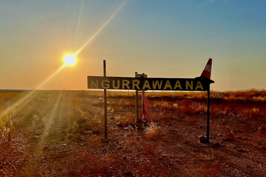The sun sets behind a sign that says 'Ngurrawaana'.