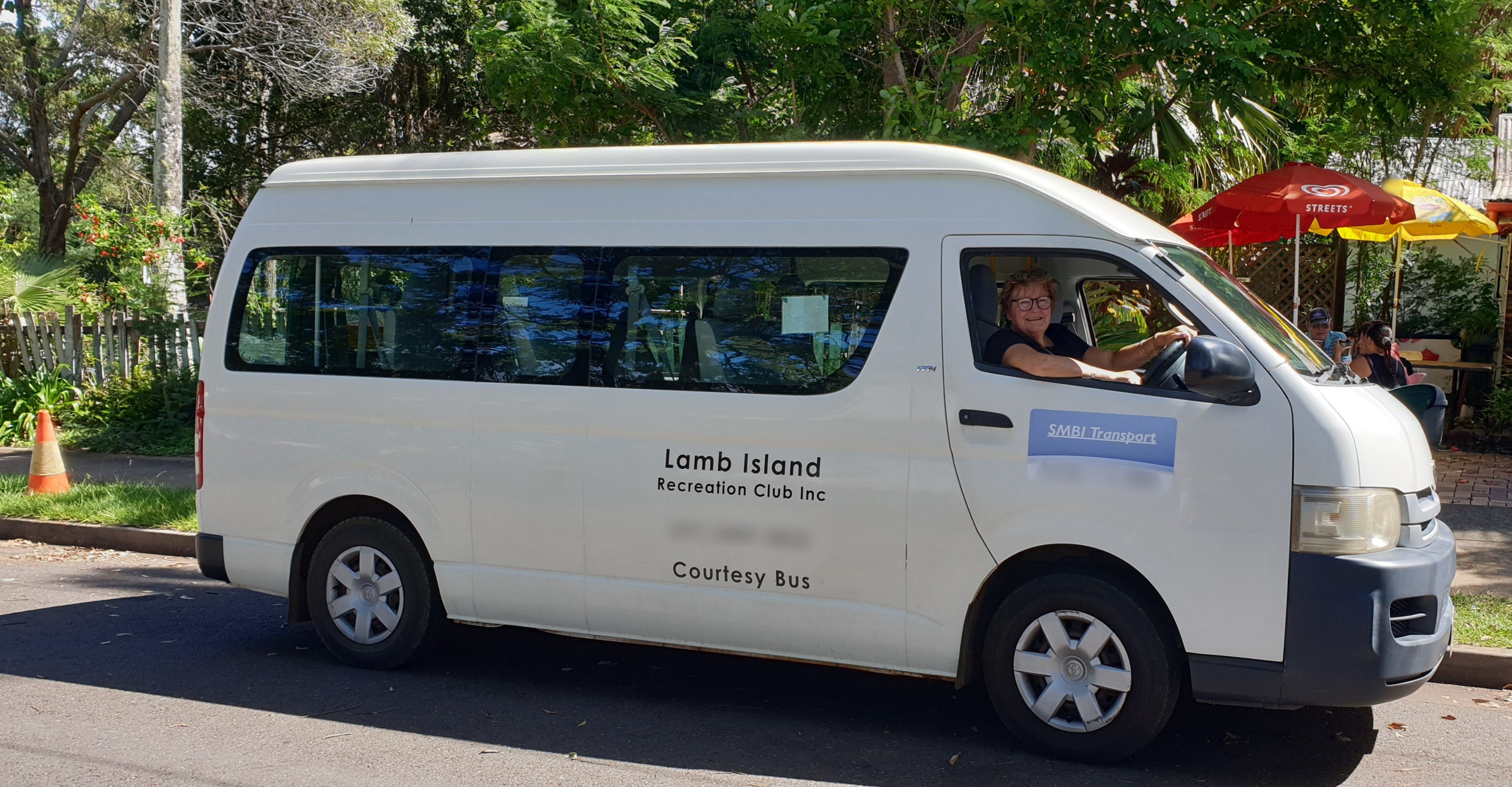 A woman in the driver's seat of a nine-seater van.