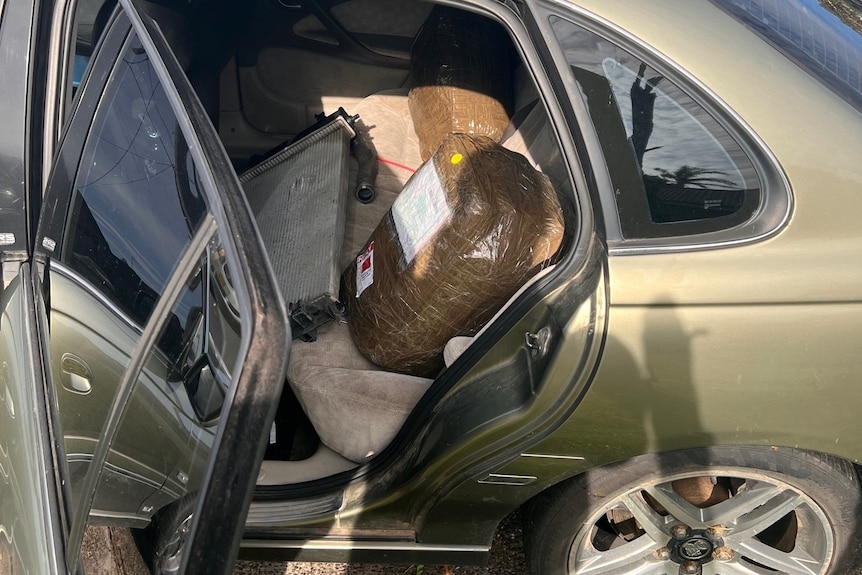 A car with its doors open and parcels inside.