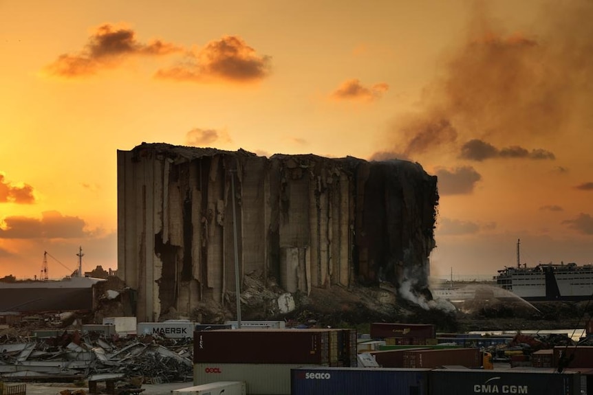 橙色的太阳落山后，消防员在贝鲁特港北部街区的筒仓中扑灭大火。