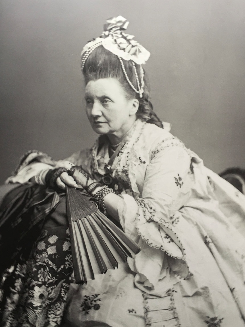 an old black and white photo of a lady in a gown