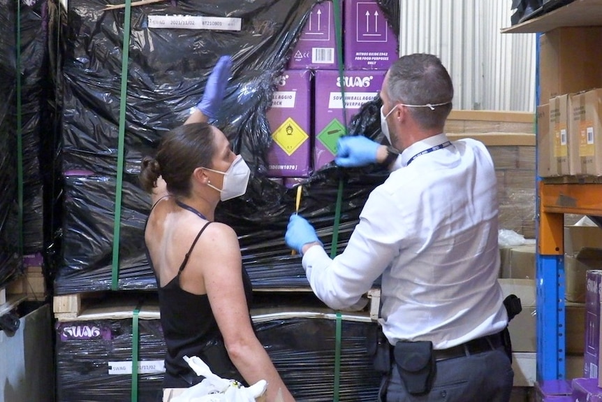 Two police officers examine stolen freight on pallets