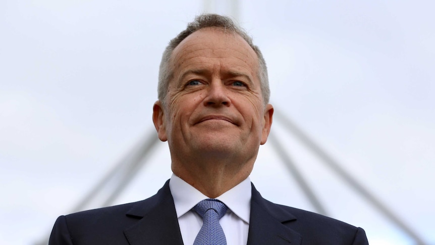 Bill Shorten grins with Parliament House blurred in the background. Shot from low down, he almost looks heroic.