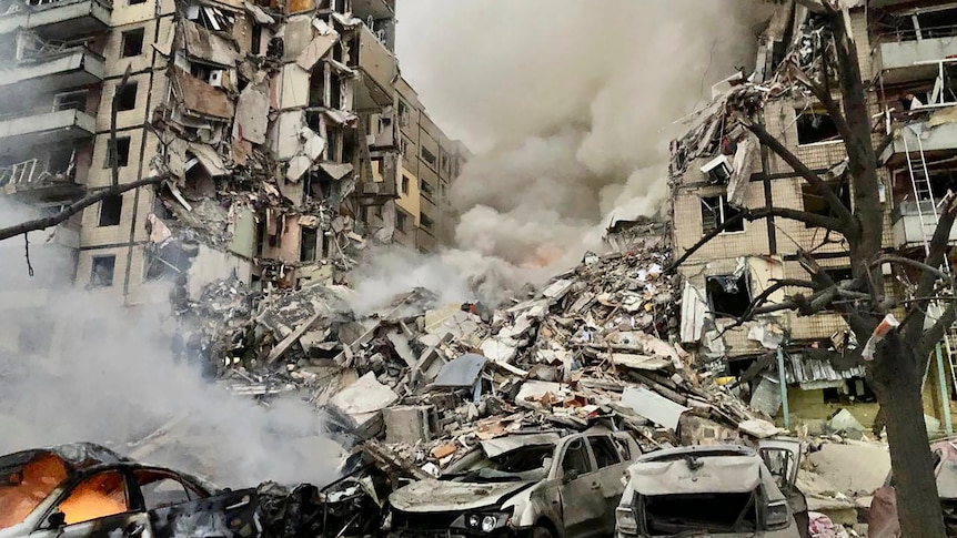 Smoke rises from destroyed multi-storey building after missile attack.