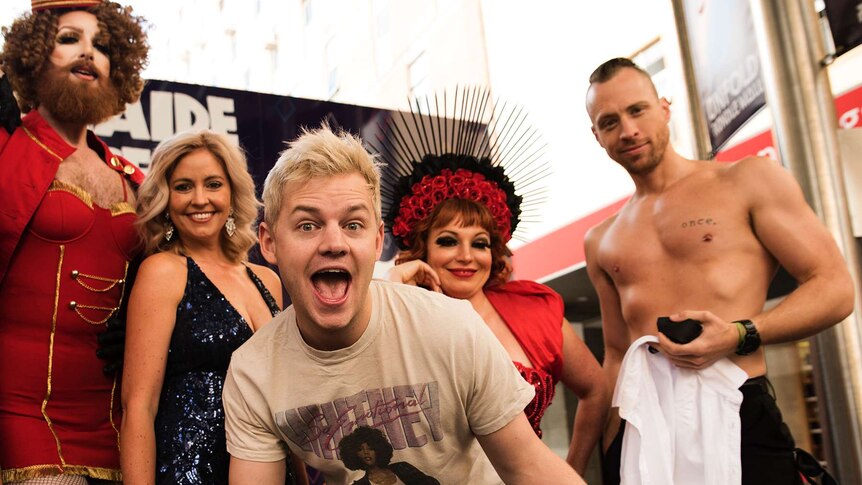 Joel Creasey laughs with Fringe performers in the background.