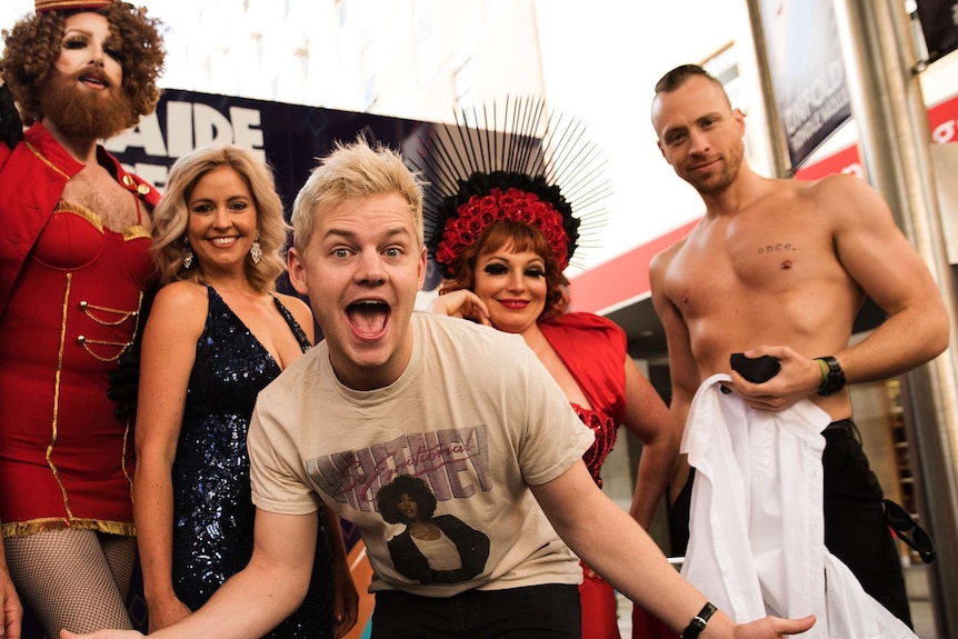 Joel Creasey laughs with Fringe performers in the background.