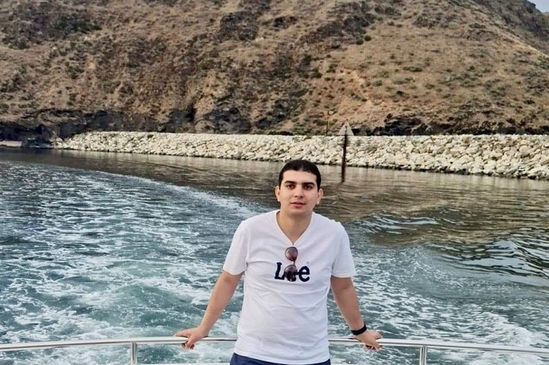 A man standing on a boat with the ocean view at his back