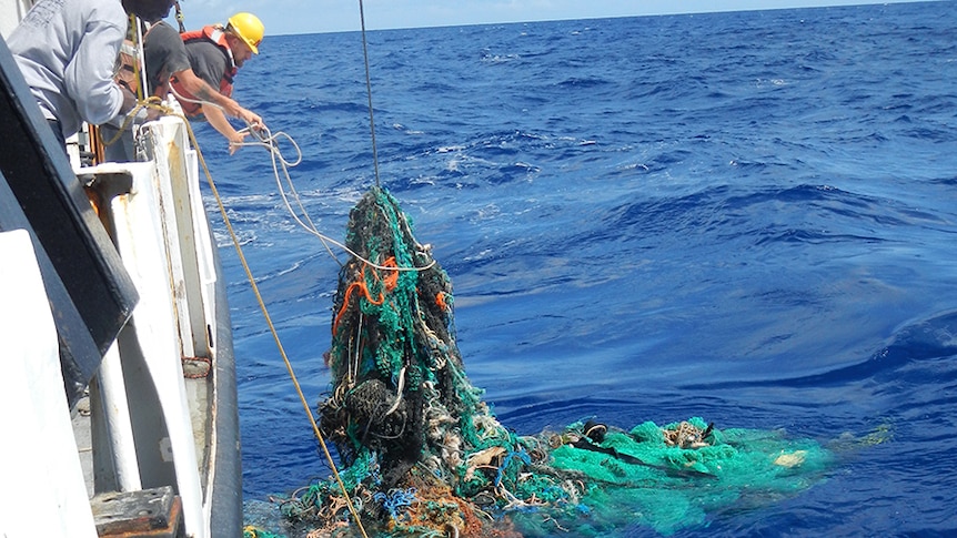 A 'ghost net' of tangled fishing nets and rubbish, being pull up onto a ship.