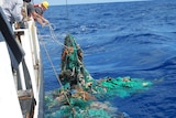 A 'ghost net' of tangled fishing nets and rubbish, being pull up onto a ship.