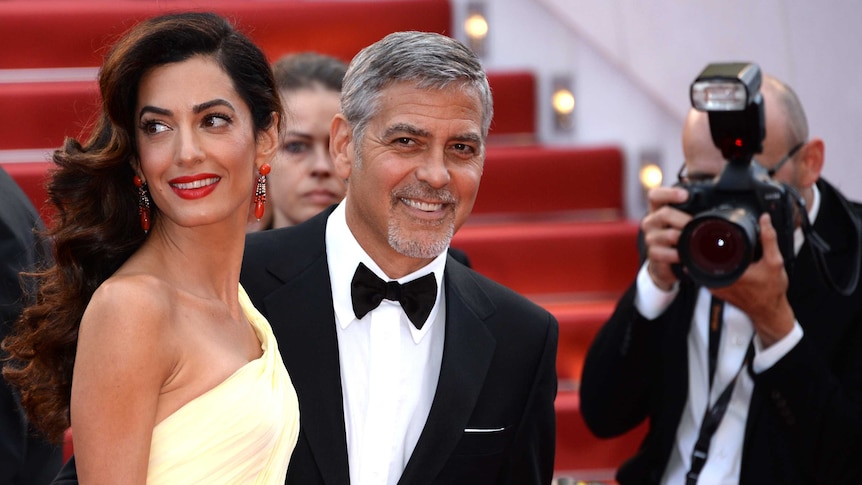 Amal and George Clooney at awards ceremony, being photographed.