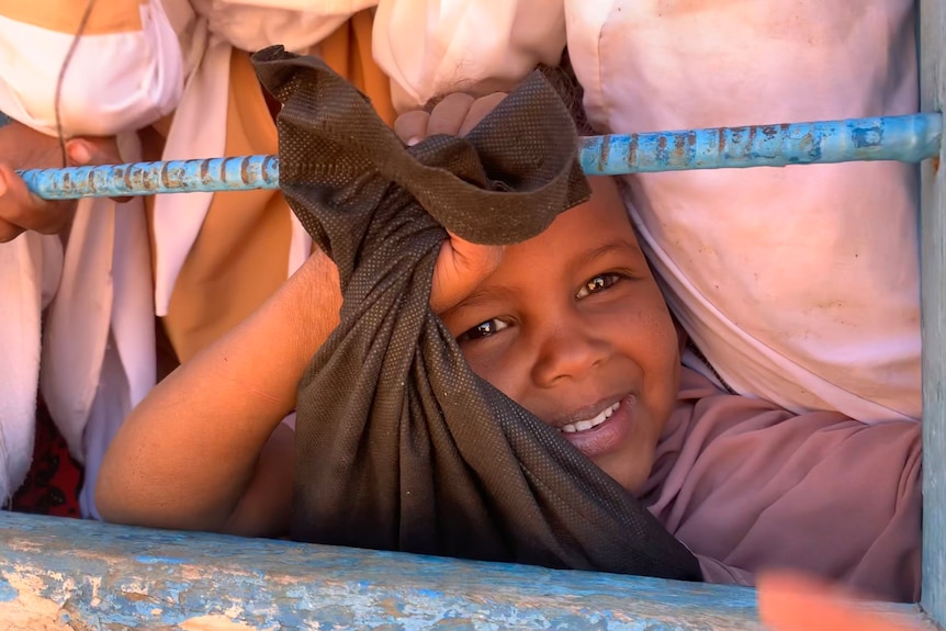 Face of a smiling child in a window.