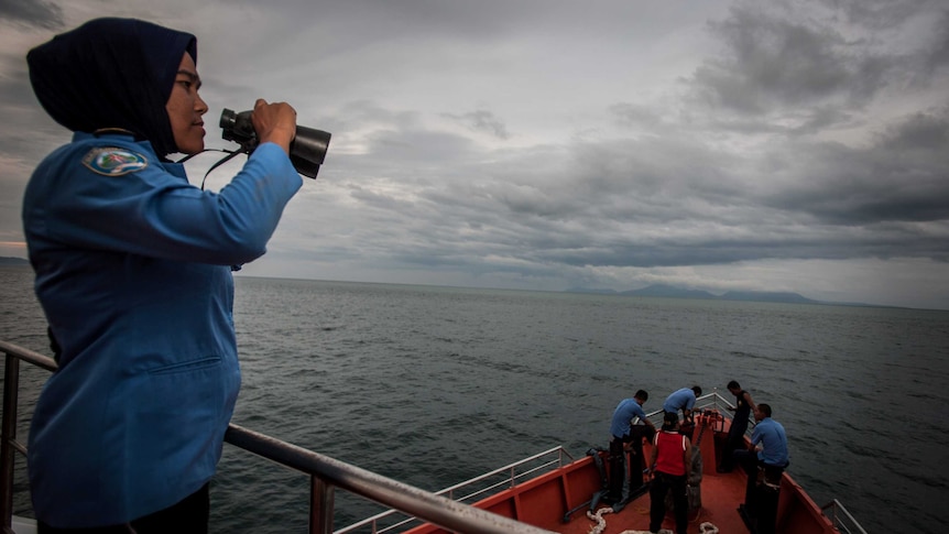 Indonesia crew use binoculars to search for the missing plane.