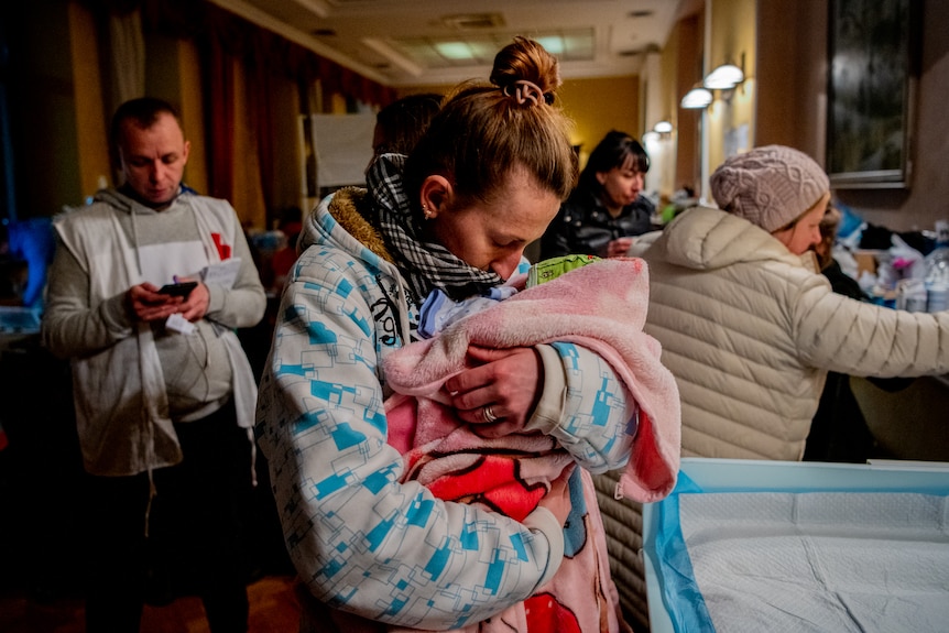 The baby is wrapped in blankets and held close to the mother's chest. 