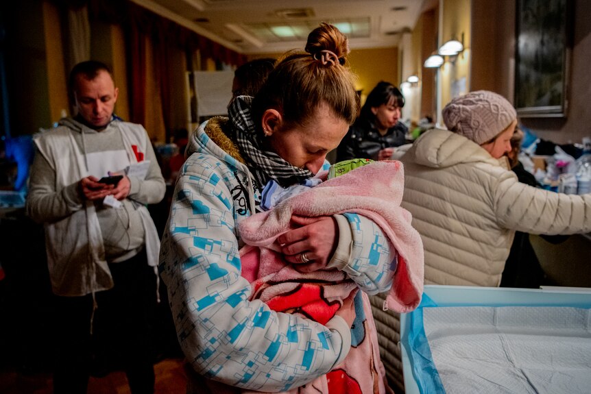 The baby is wrapped in blankets and held close to the mother's chest. 