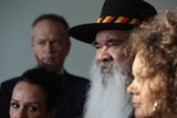 Pat Dodson, wearing a black hat with red and yellow trim, stands with Malarndirri McCarthy, Linda Burney, and Bill Shorten.