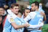 A group of Melbourne City A-League Men players embrace as they celebrate a goal.