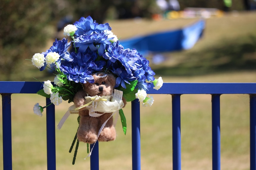 A teddy bear and flowers left at the Hillcrest Primary School.