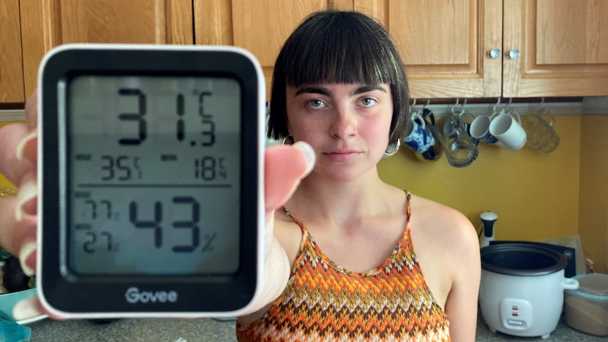 A woman with dark hair holds up a thermometer.