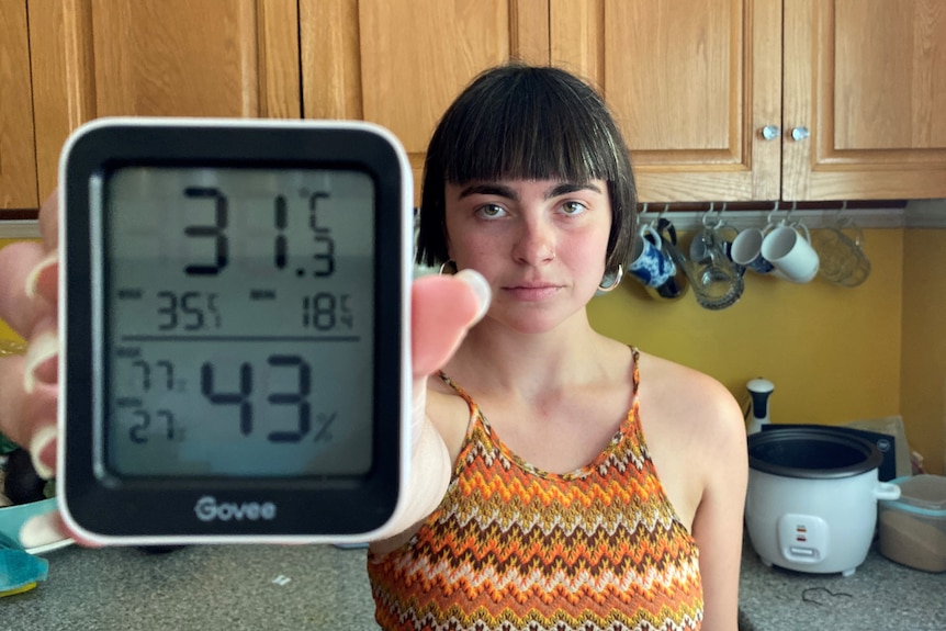 A woman with dark hair holds up a thermometer.