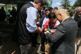 A group of Chinese delegates gather around a Tasmanian dairy company owner to swap business cards.