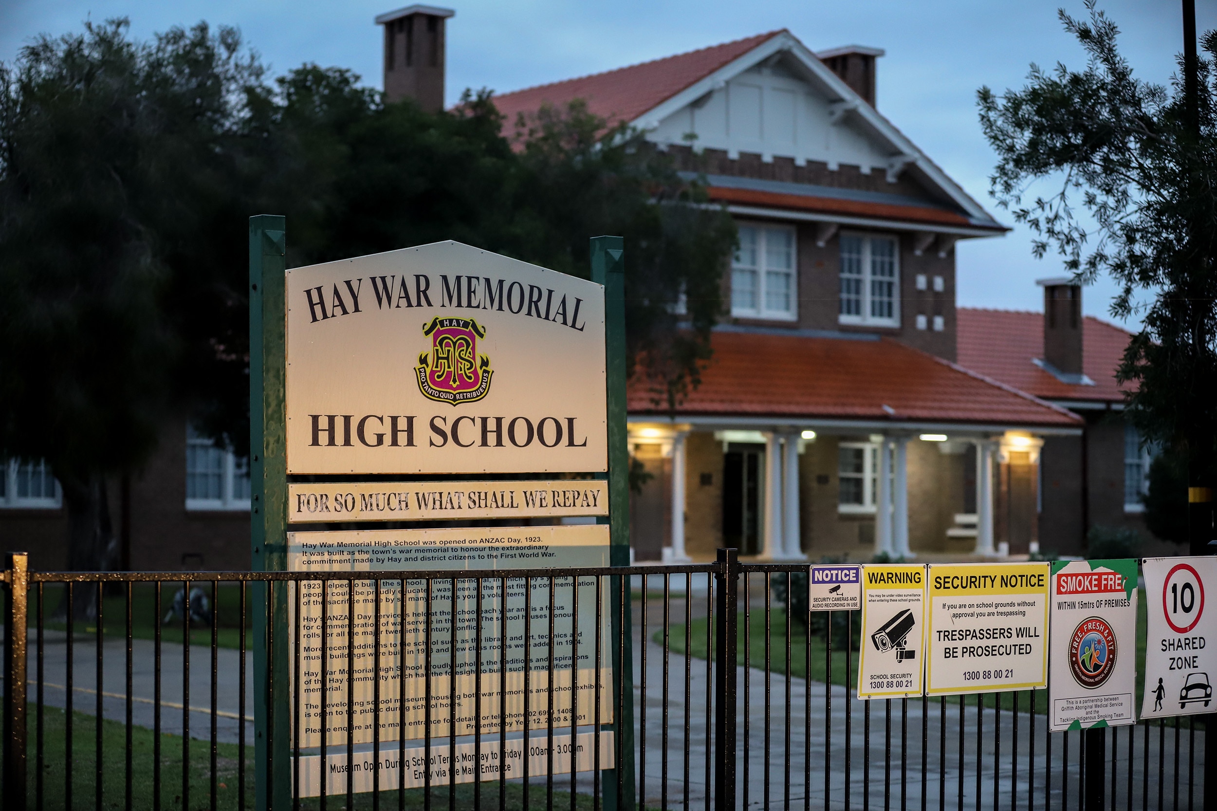 A historic red brick building with a sign in front reading 'Hay War Memorial High School' 