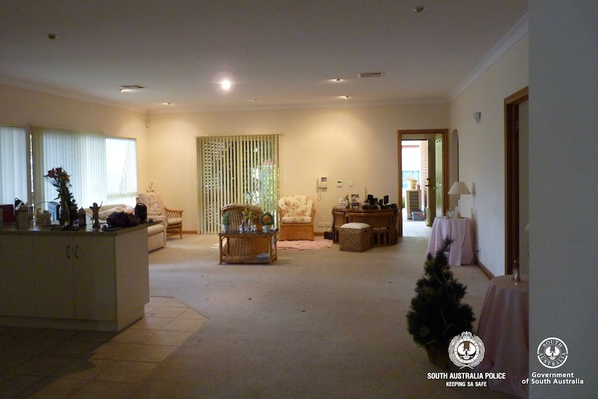 The interior of a house.  You can see three wicker chairs and a cream-colored couch.  There is also a Christmas tree.